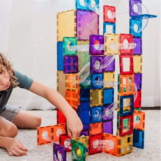 A child playing with connetix magnetic tiles rainbow ball run 92 piece pack with clear tubes