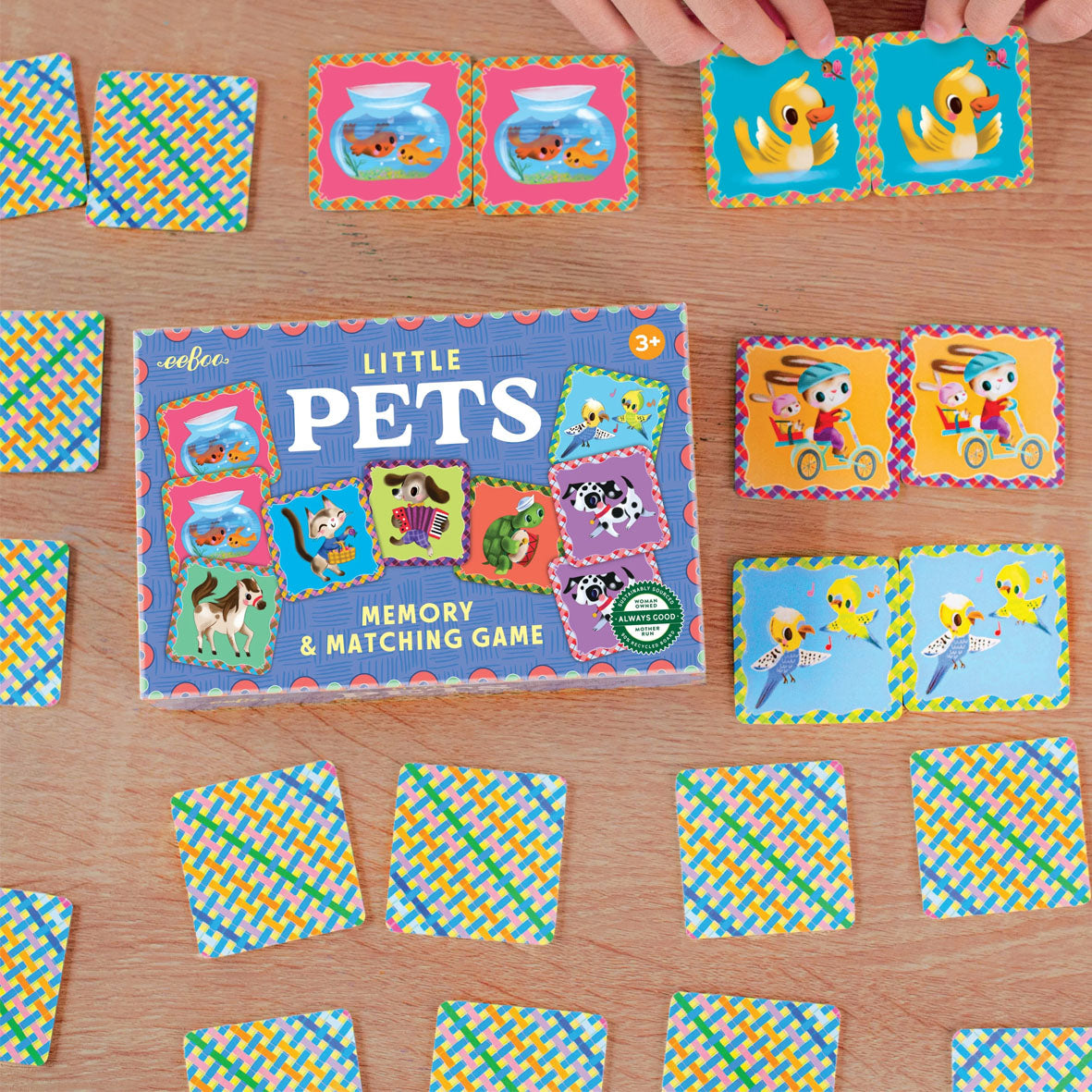 A children's memory and matching game called Little Pets by eeBoo, shown with colourful animal cards arranged on a wooden tabletop.